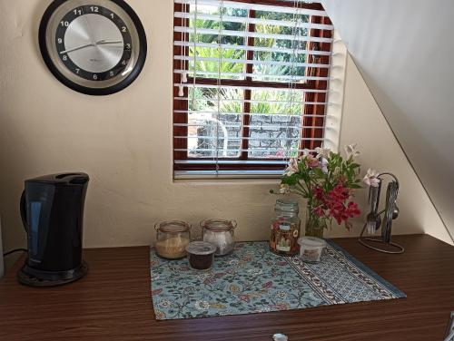 a table with a clock on the wall and a window at Little Tree Loft in Uitenhage