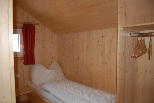 a small room with a bed in a wooden wall at Chalet Sonnenschein in Hohentauern