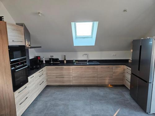Una cocina con armarios de madera y un fregadero y una ventana. en Logement proche Bourboule 12 personnes, en Massanges