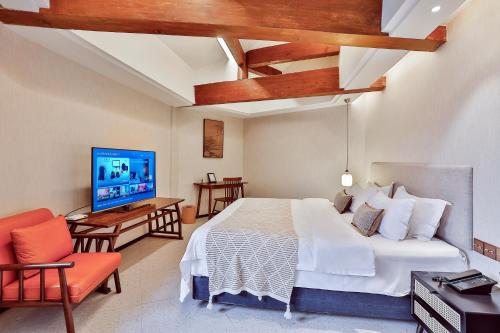 a bedroom with a bed and a tv in a room at Yurong West Lake Cottage Resort Hotel Hangzhou in Hangzhou