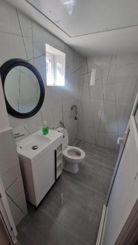 a white bathroom with a toilet and a mirror at Closca Apartment 1 Max in Floreşti