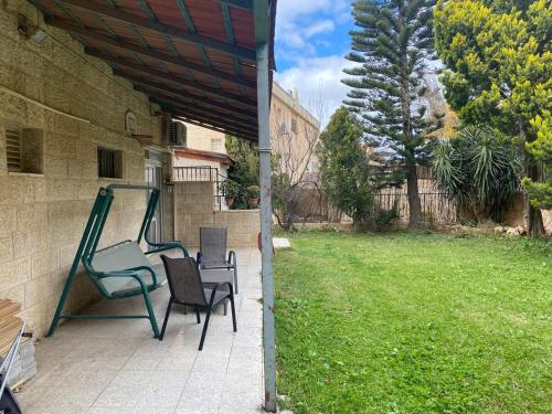 a patio with two chairs and a swing at דירת גן מרווחת במיקום מעולה עם נטפליקס חינמי in Ma'ale Adumim