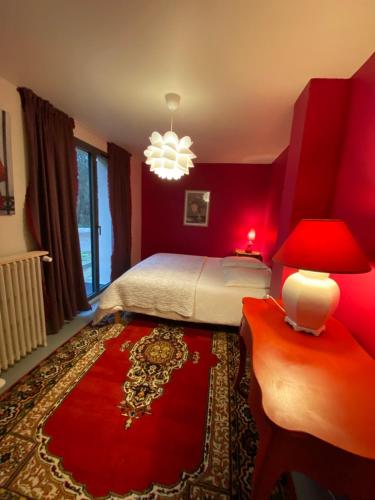 - une chambre rouge avec un lit et une table avec une lampe dans l'établissement La maison de Crponne, à Craponne