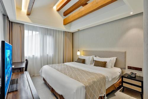 a bedroom with a large bed and a flat screen tv at Yurong West Lake Cottage Resort Hotel Hangzhou in Hangzhou