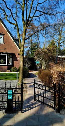 a fence in front of a house with a tree at Veluws Huisje in Apeldoorn