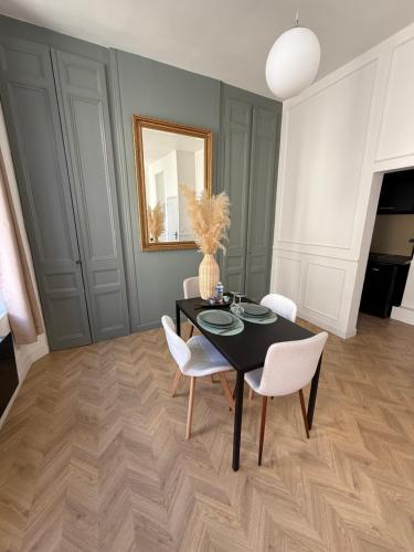 une salle à manger avec une table noire et des chaises blanches dans l'établissement L'Instant Chic - Appartement à 5min à pied de Nausicaa, plage, centre Ville, à Boulogne-sur-Mer