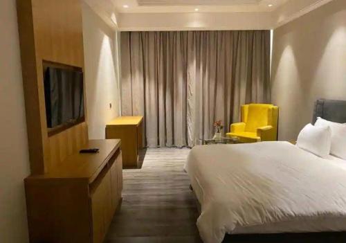 a hotel room with a large bed and a yellow chair at Hoatel Abha in Alīgarh