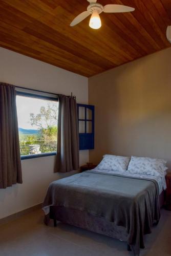 a bedroom with a bed with a ceiling fan and a window at Casa Portal do Pati in Lençóis