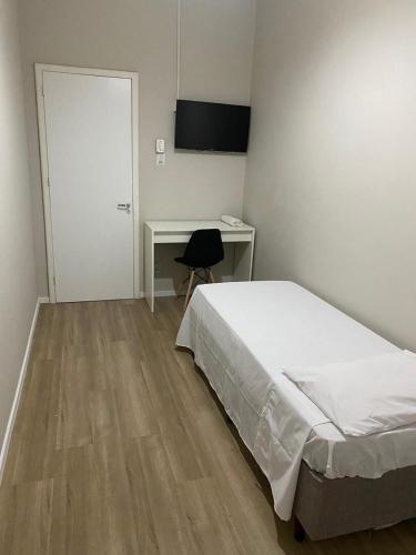 a bedroom with a bed and a desk and a door at Hotel life Ijuí in Ijuí