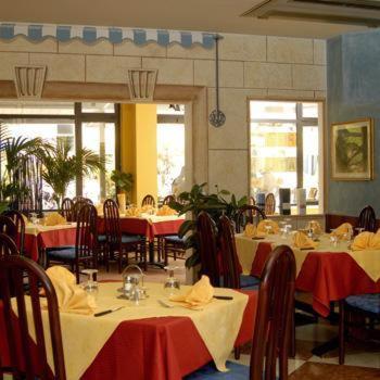 a restaurant with tables and chairs with red table cloth at Hotel Centro Turistico Gardesano in Bussolengo