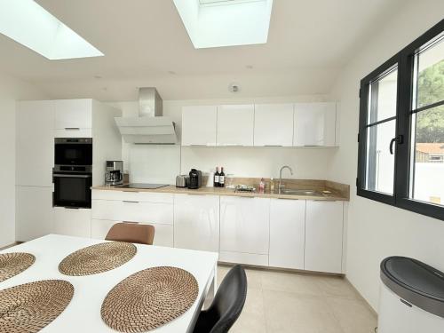 une cuisine avec des armoires blanches et une table avec des chaises dans l'établissement La petite grole, à Saint-Pierre-dʼOléron