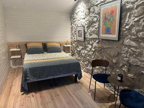 une chambre avec un lit et un mur en pierre dans l'établissement Les Gîtes du Soleil Vert, à Meyrannes