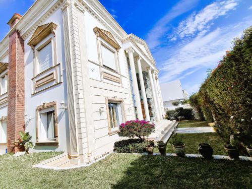 a white house with potted plants on the lawn at L'Orchidée - Suites de Luxe avec Piscine Chauffée et Vue sur le Lac de Tunis in Tunis