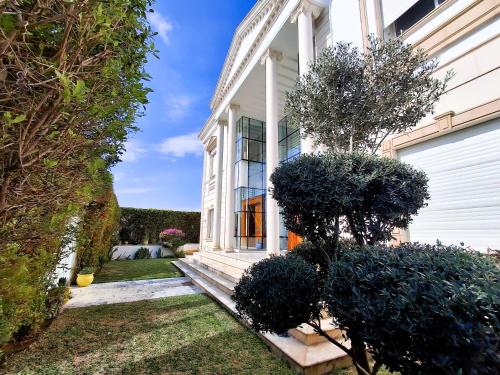 a white house with a yard with bushes at L'Orchidée - Suites de Luxe avec Piscine Chauffée et Vue sur le Lac de Tunis in Tunis