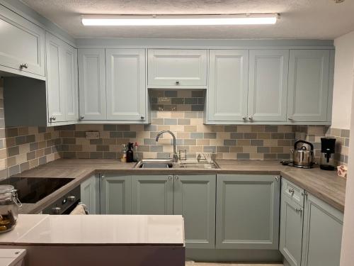 eine Küche mit weißen Schränken und einer Spüle in der Unterkunft Home By The Sea in Eastbourne