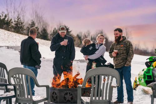 a group of people standing around a fire in the snow at The View Boutique Hotel Suites in Tully