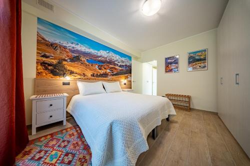 a bedroom with a white bed and a painting on the wall at Piazza Castello LT in Chiavenna