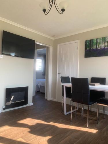 a living room with a table and chairs and a fireplace at Dragon Chalet 1 , 155 Sunbeach Holiday Village, Scratby in Scratby
