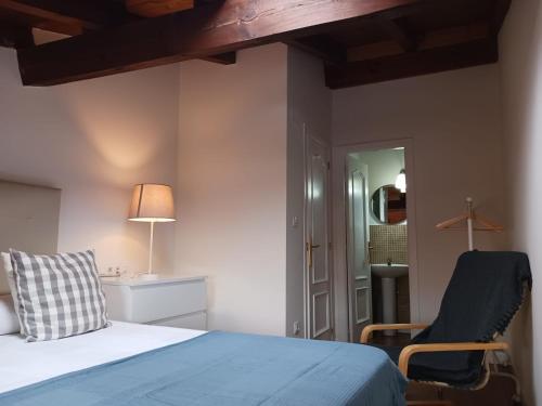 ein Schlafzimmer mit einem Bett, einem Stuhl und einem Spiegel in der Unterkunft El ático de Esther in Haro