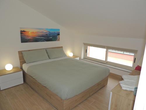 Un dormitorio con una cama grande y dos ventanas. en LA SCOGLIERA - Apartment, en Stazzo