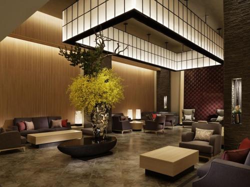 a lobby with couches and chairs and a plant at Kobe Minato Onsen Ren in Kobe