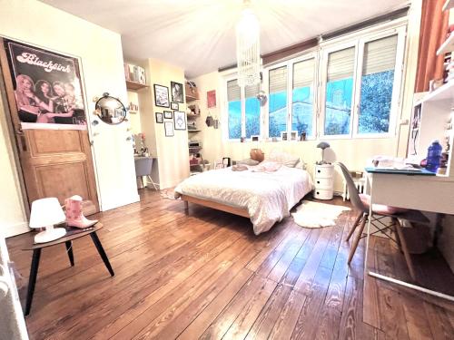 a bedroom with a bed and wooden floors and windows at Au Petit Bonheur in Talence