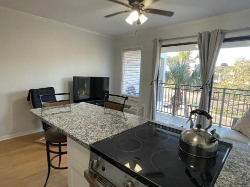 a kitchen with a stove top oven next to a living room at Coastal Getaway Oceanview Condo in Hilton Head in Hilton Head Island