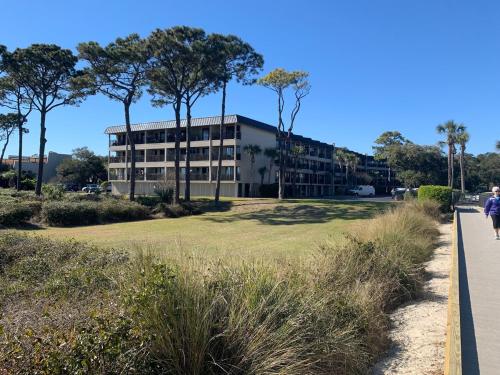 a building on the side of a beach with a person walking on a sidewalk at Coastal Getaway Oceanview Condo in Hilton Head in Hilton Head Island
