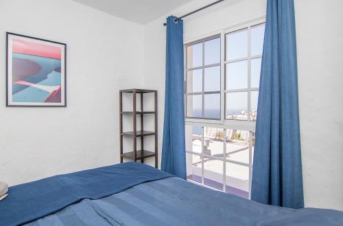 a bedroom with a blue bed and a large window at Calle Goya 108 in Arguineguín