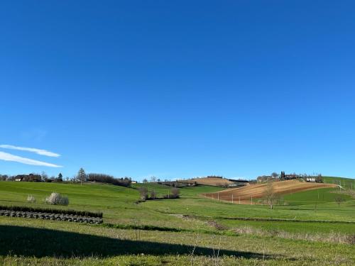 a field with a farm in the distance at Cascina Mima - Monferrato in Quargnento