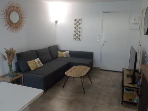 un salon avec un canapé bleu et une table dans l'établissement Appartement P2 proche plage, au Grau-du-Roi