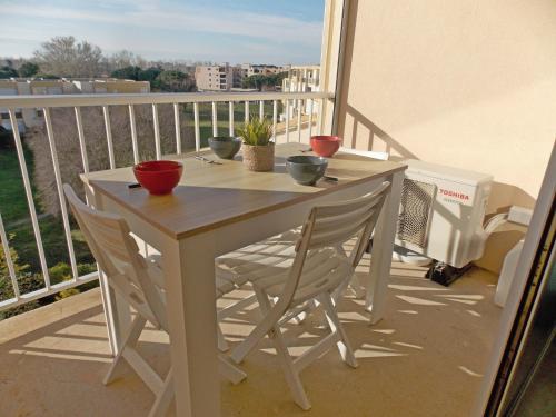 une table blanche et des chaises sur un balcon dans l'établissement Appartement P2 proche plage, au Grau-du-Roi