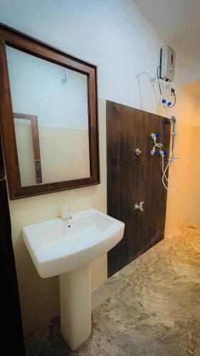 a bathroom with a white sink and a mirror at Hotel Milenium in Kurundankulama