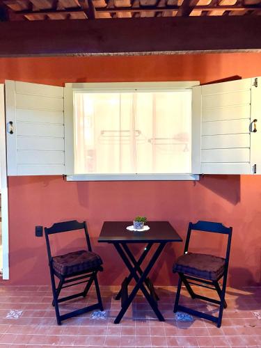 a table and two chairs sitting under a window at XIQUE XIQUE ITAUNAS HOSPEDARIA in Itaúnas