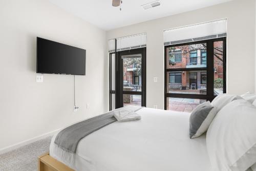 a white bedroom with a bed and a flat screen tv at Spacious Comfort Near Downtown Hotspots in Arlington
