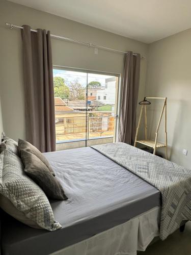 a bedroom with a bed and a large window at Apartamento Palmeira in Formosa