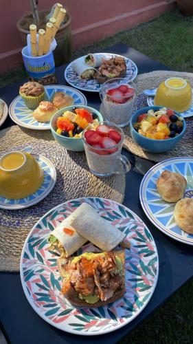 a table with plates of food and bowls of fruit at XIQUE XIQUE ITAUNAS HOSPEDARIA in Itaúnas