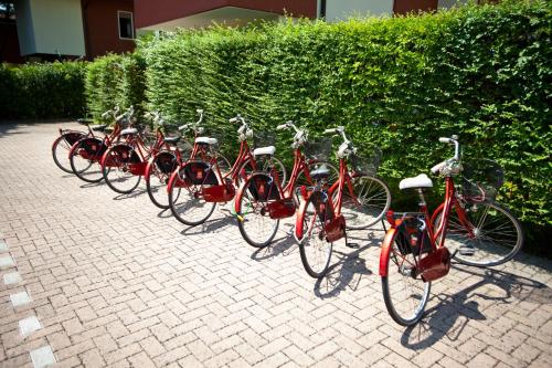 a row of red bikes parked next to a hedge at Nice Hotel Bibione in Bibione
