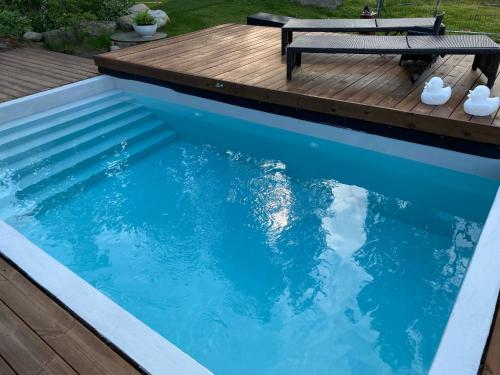 una piscina con terraza de madera y un banco en Villa Ensola with pool, en Savonlinna