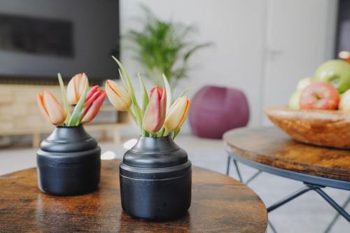 two black vases with flowers in them on a table at Kaßberg Domizil in Chemnitz
