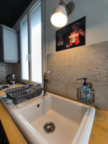 La cuisine est équipée d'un évier blanc et d'une télévision murale. dans l'établissement Appartement Vintage spacieux centre ville, à Pau