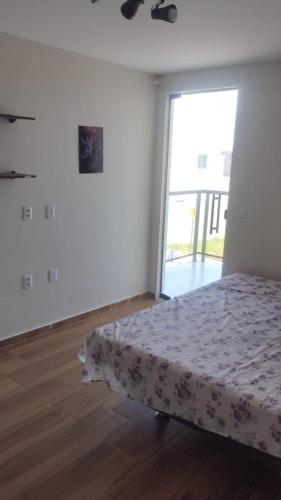 a white room with a bed and a large window at Casa de Férias - Refúgio Arembepe in Camaçari