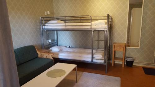 a room with a bunk bed with a couch and a table at Sjugare Gård Bed & Breakfast in Leksand