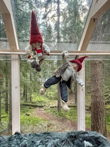 two dolls hanging on a pole in a window at Wood Wise Glasshouse Glamping in Bengtsfors