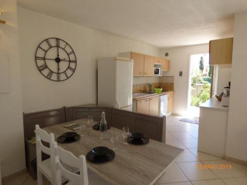 une cuisine avec une table et une horloge au mur dans l'établissement Villa Narbonne Beach T5, à Narbonne-Plage