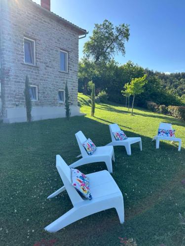 three white benches sitting in the grass in front of a building at Εn Kanalion in Kanália