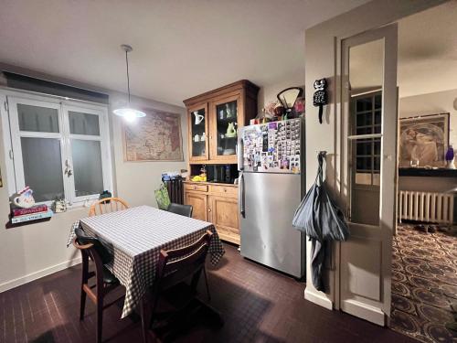 a kitchen with a table and a refrigerator at Au Petit Bonheur in Talence