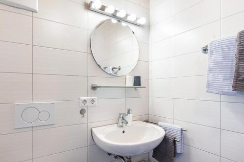 a white bathroom with a sink and a mirror at Winzercafé Neipperg in Brackenheim
