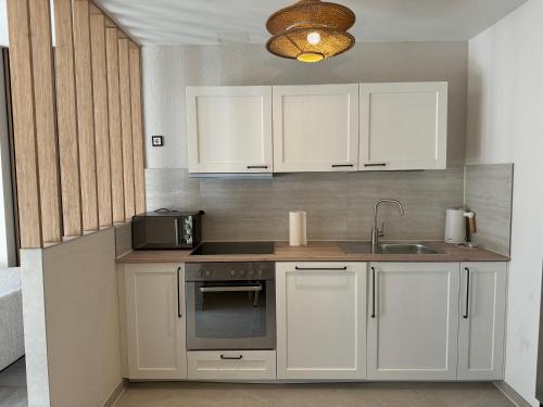 Una cocina con gabinetes blancos, un fregadero y un microondas. en L&K Apartment, en Metzingen