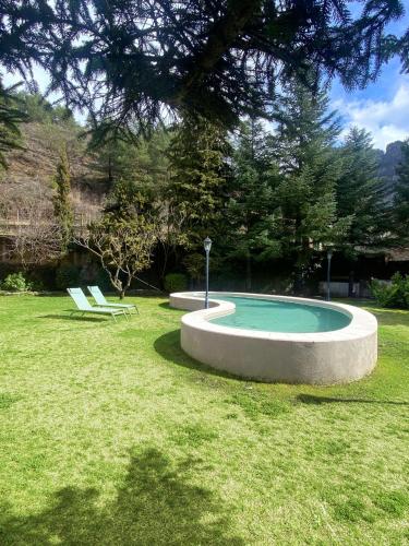 a small pool in a yard with two chairs at La Torre de Guardiola in Guardiola de Berguedà